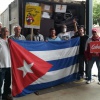 Die Helfer*innen stehen mit der kubanischen Flagge am vollbeladenen Container.