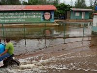 ein Moped fährt über eine überflutete Straße in einem kubanischen Dorf
